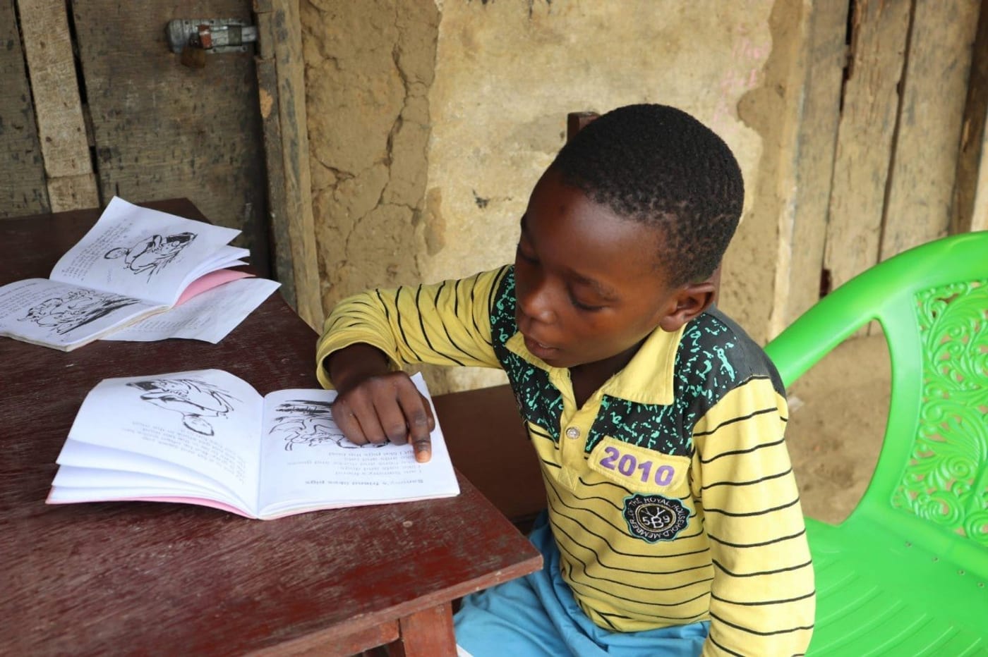 A young learner focuses on reading a book during a LIPACE foundational learning session